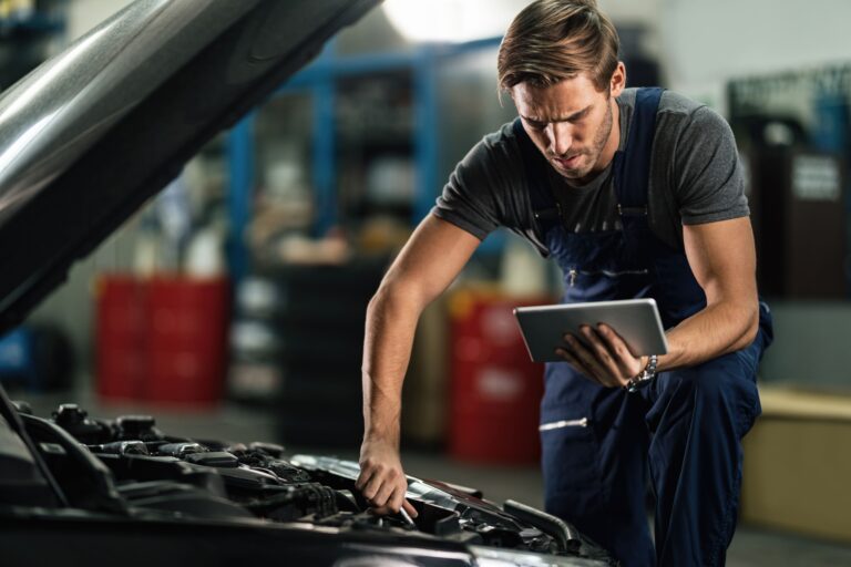 garagiste effectuant le contrôle technique complet d'une auto à l'aide de son logiciel professionnel sur tablette mobile